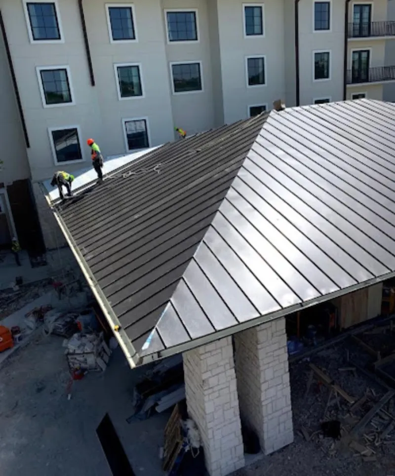 Crew installing standing seam metal roof panels on a commercial project in Atmore